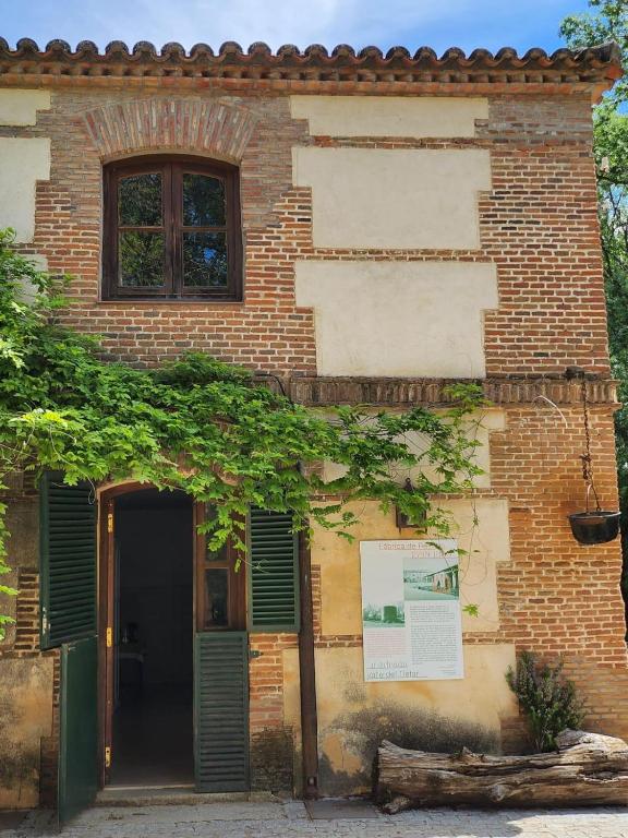 a brick building with green shutters and a door at La Resinera in La Adrada