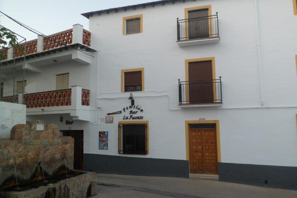 un edificio blanco con puertas marrones y balcones. en Pensión La Fuente, en Yegen