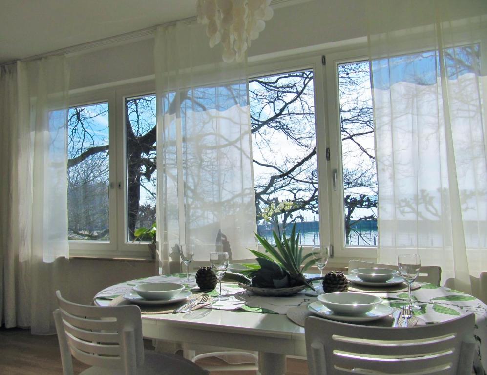 una sala da pranzo con tavolo, sedie e finestre di Ferienwohnung Seepromenade a Costanza
