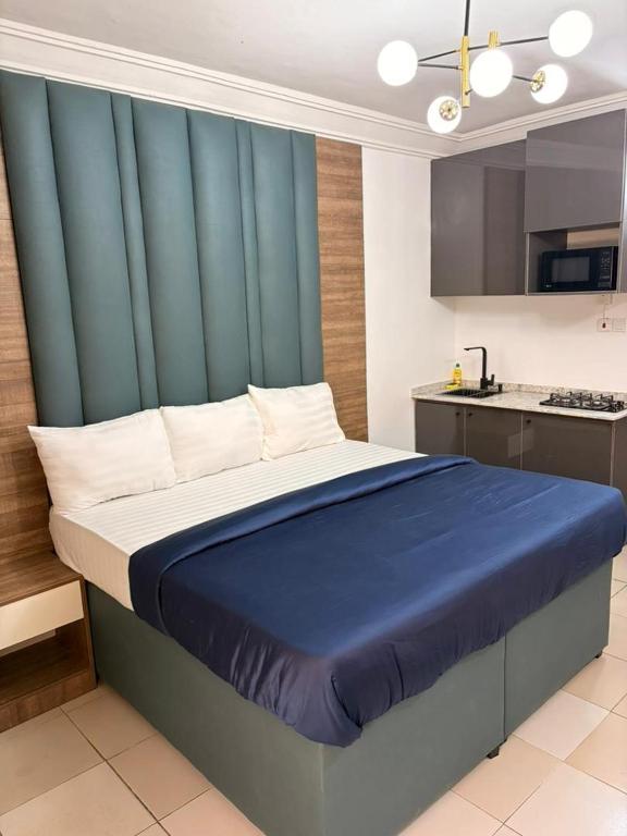 a bedroom with a large bed with a blue headboard at OD-VICK'S PLUSH STUDIOS, Utako in Abuja