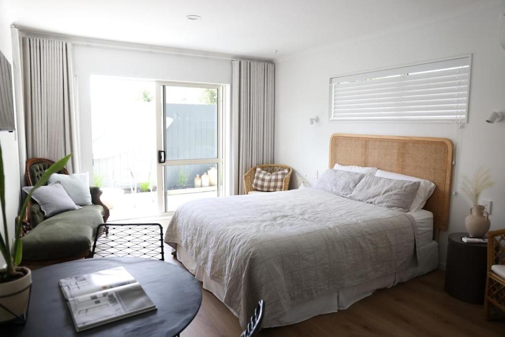a bedroom with a bed and a chair and a window at Coastal Calm Papamoa in Tauranga