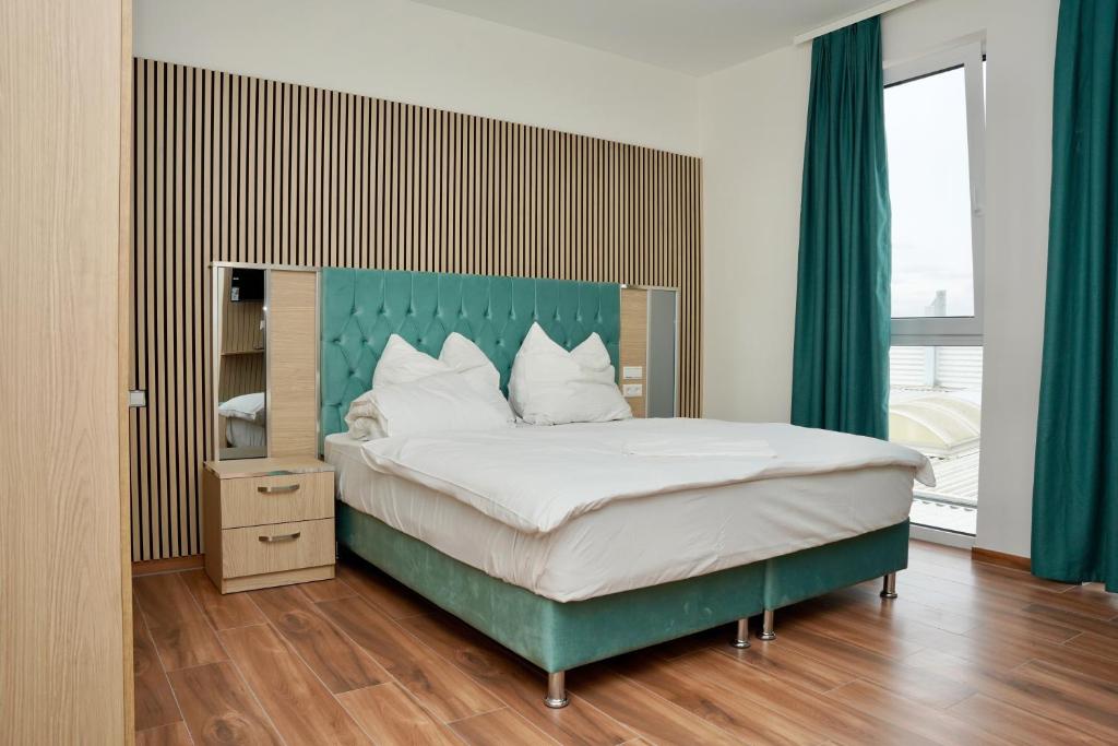 ein Schlafzimmer mit einem großen Bett mit grünem Kopfteil in der Unterkunft Mersa Hotel in Backnang