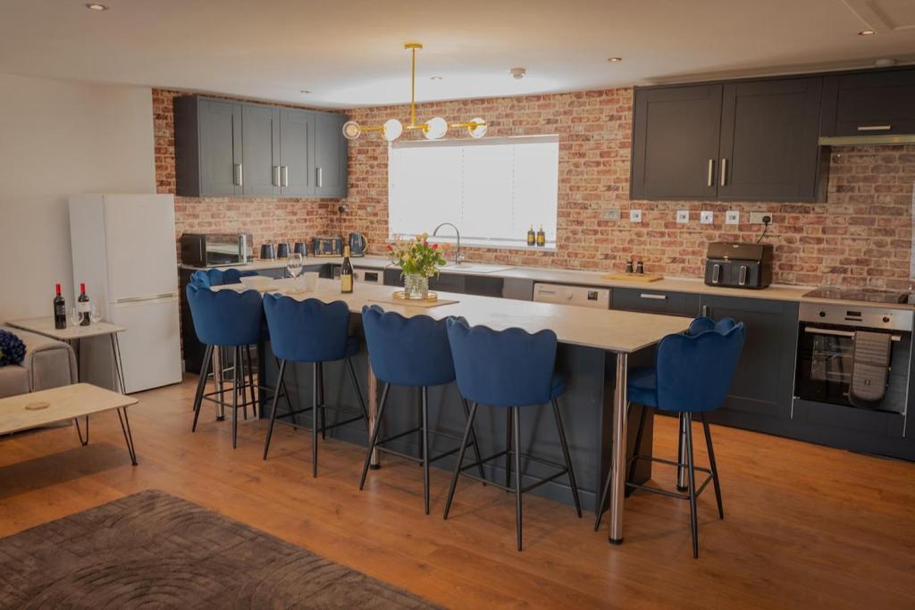a kitchen with a table and blue bar stools at Easterly Sleeps in Lowestoft