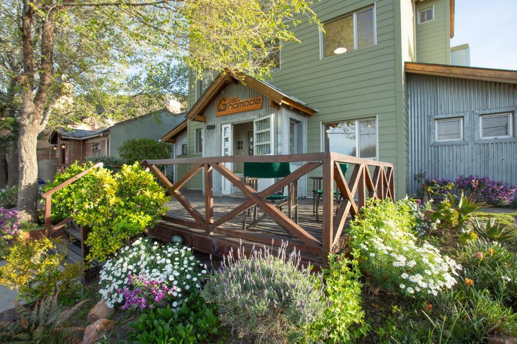 a wooden bridge in front of a house with flowers at Del Nomade Hosteria Ecologica in Puerto Pirámides