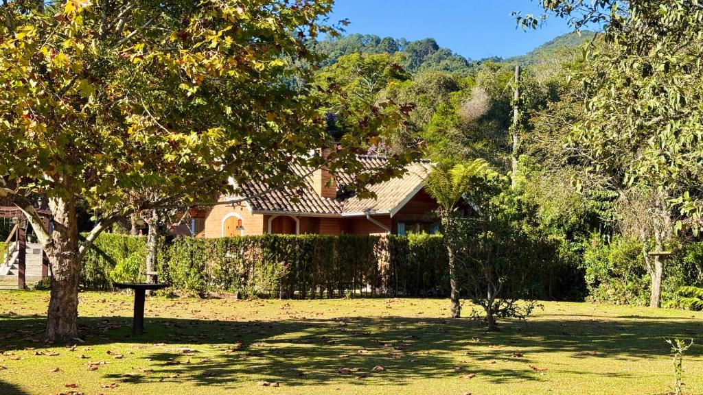a house with a tree in front of a yard at Pousada Villa do Luar by Concavus in Monte Verde