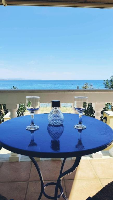 a blue table with three wine glasses on a balcony at Pantelis Studio in Paralia Agias Foteinis