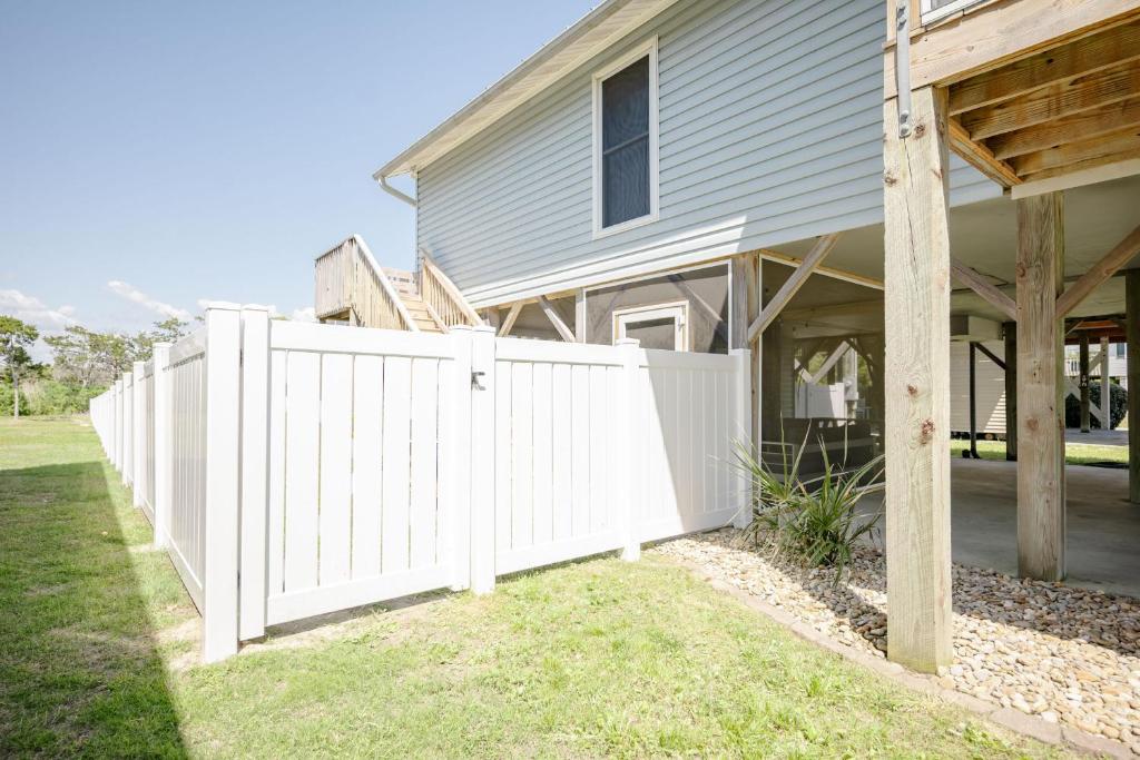 a white fence in front of a house at Changes In LAttitude by Oak Island Accommodations in Oak Island