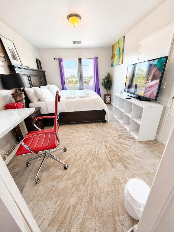 a bedroom with a bed and a desk and a red chair at Penn Signature Airport Short Term Rental PHX in Phoenix