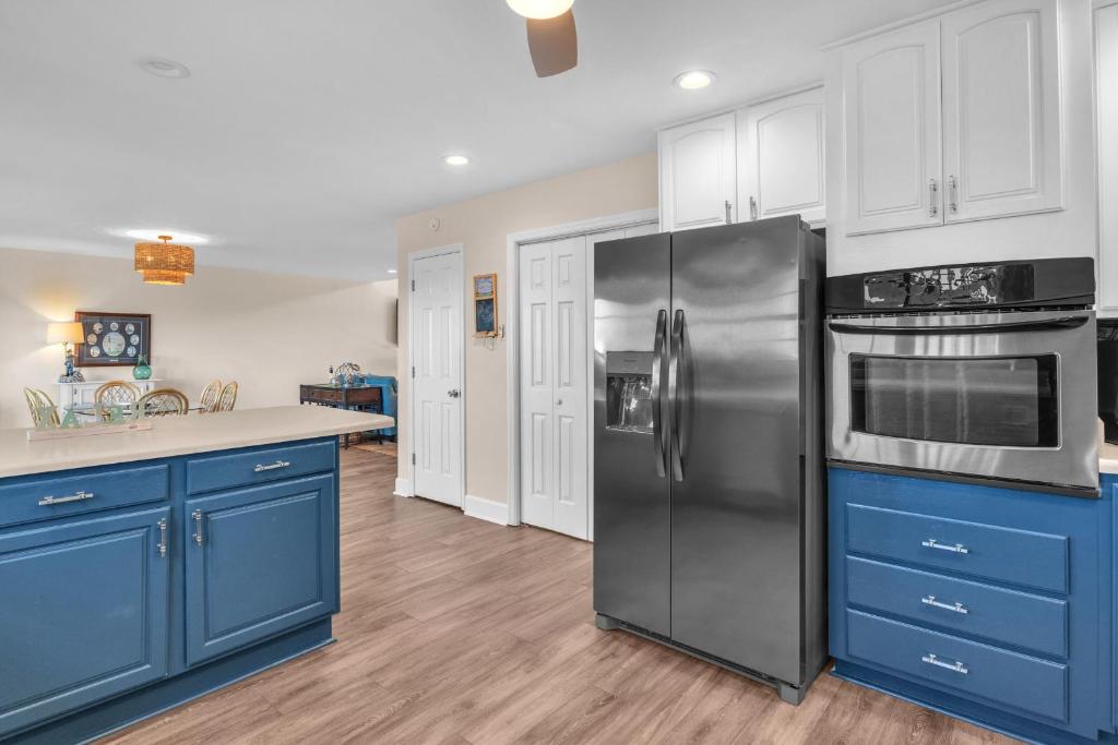 a kitchen with blue cabinets and a stainless steel refrigerator at Clear For Take Off by Oak Island Accommodations in Caswell Beach