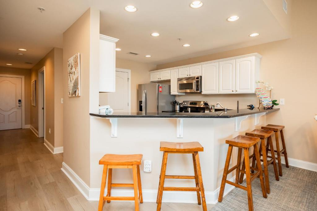 a kitchen with wooden stools and a counter top at Clearly Hooked by Oak Island Accommodations in Oak Island