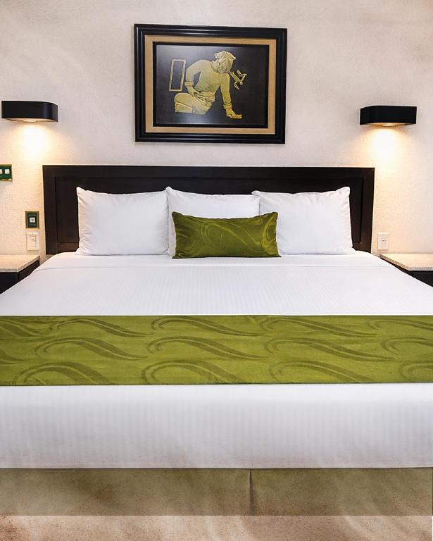 a large white bed with a green blanket on it at Eco City Hoteles in Tuxtla Gutiérrez