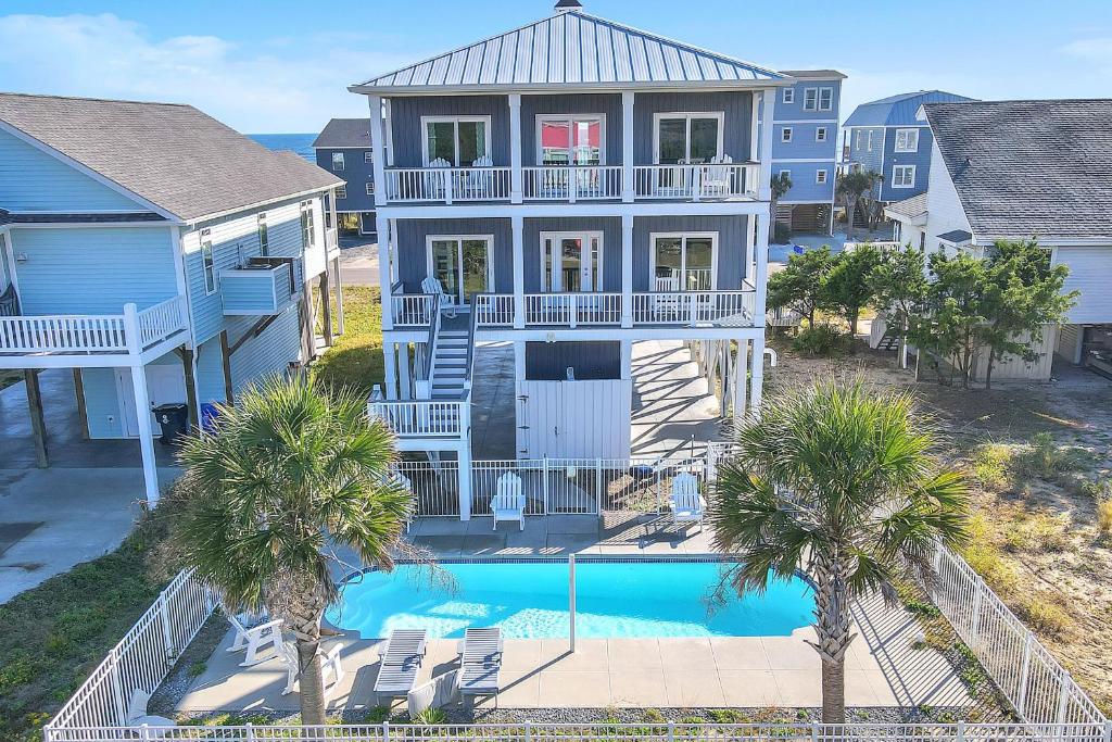 an aerial view of a house with a pool and palm trees at Conch Out by Oak Island Accommodations in Oak Island
