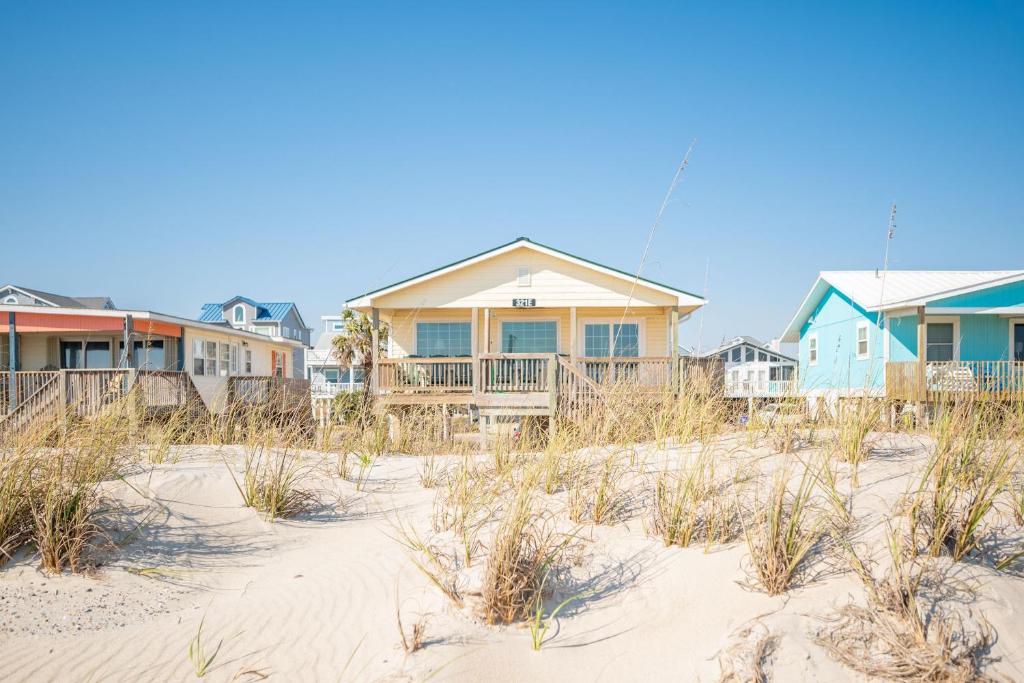 a row of houses on a beach with sand at Dip Inn by Oak Island Accommodations in Oak Island