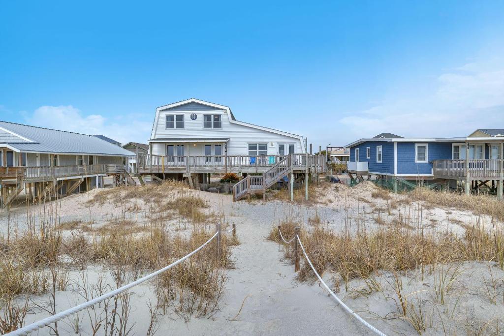 a row of houses on a beach with sand and houses at Divine Intervention by Oak Island Accommodations in Oak Island