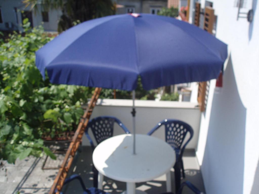 Ein Tisch und Stühle mit einem blauen Sonnenschirm auf einem Balkon in der Unterkunft ABC Lešnik in Koper