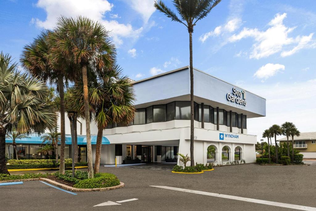 a building with palm trees in a parking lot at Club Wyndham Sea Gardens in Pompano Beach