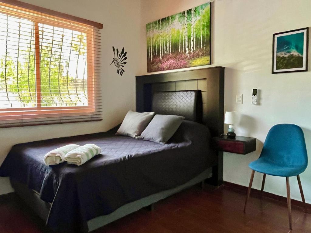 a bedroom with a bed and a blue chair at Le Colibri - 1 Min Beach - Pool - Serenity in La Peñita de Jaltemba