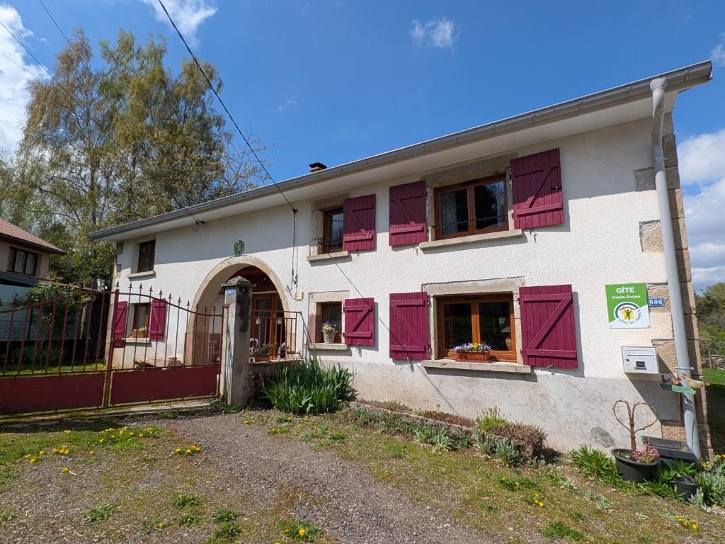 a white building with red shutters on the windows at Gîte paisible dans ancienne ferme comtoise avec animaux acceptés - FR-1-583-416 in Saint-Bresson