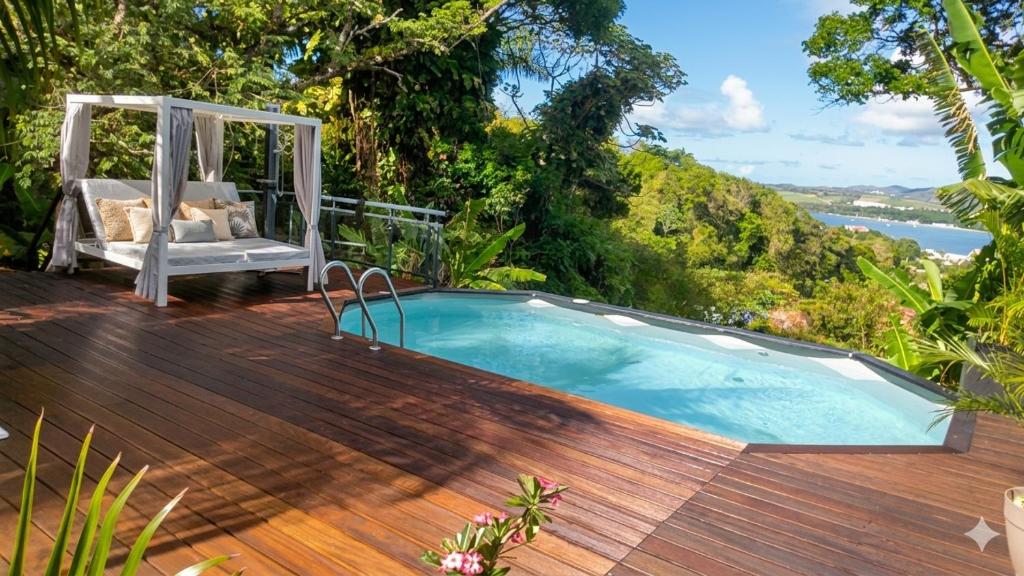 a swimming pool on a wooden deck with a swing at L'Ombre de L'Eucalyptus Bel Appart Chambre-Salon Vue Mer & Piscine in La Trinité