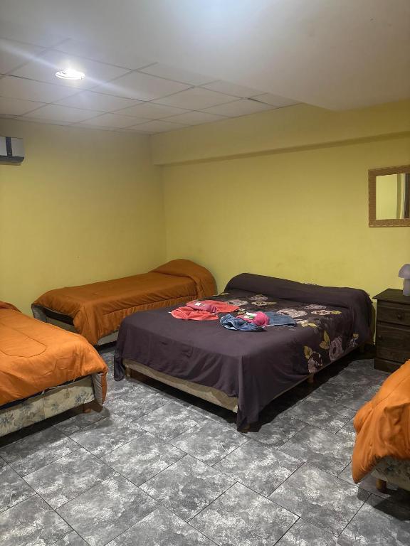three beds in a room with yellow walls at Hotel Norte in Río Tercero