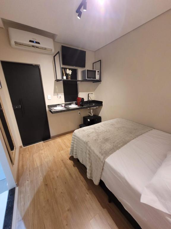 a bedroom with a bed and a desk in it at Studio Moderno e Prático Wi-Fi Rápido e AC in Ribeirão Preto