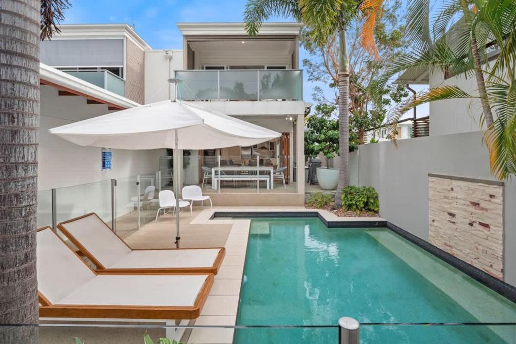 a house with a swimming pool and an umbrella at Pet Friendly Modern Oasis with Private Pool in Noosaville