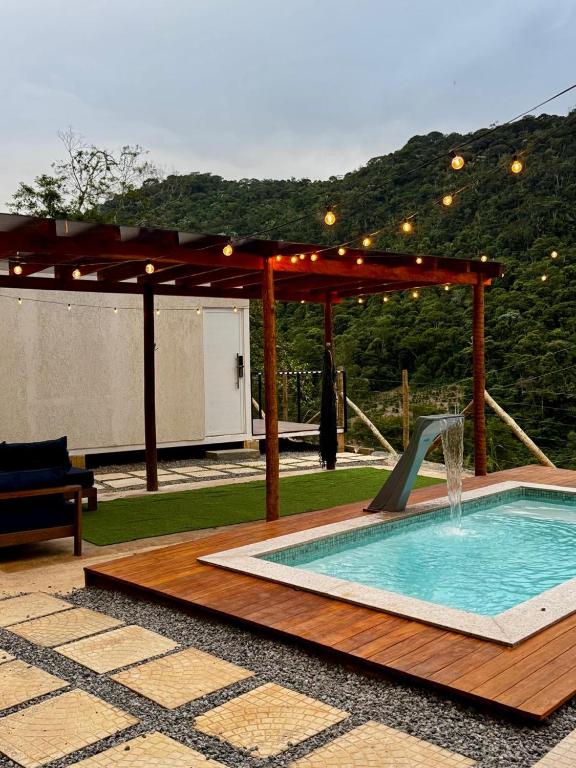 a swimming pool with a pergola and a water fountain at Chalé loft reserva Refúgio nas Montanhas in Marechal Floriano
