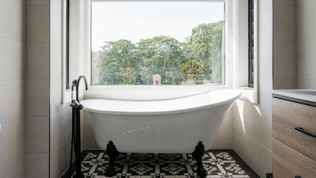 a bath tub in a bathroom with a window at Kingfisher Cottage in Broughton Vale