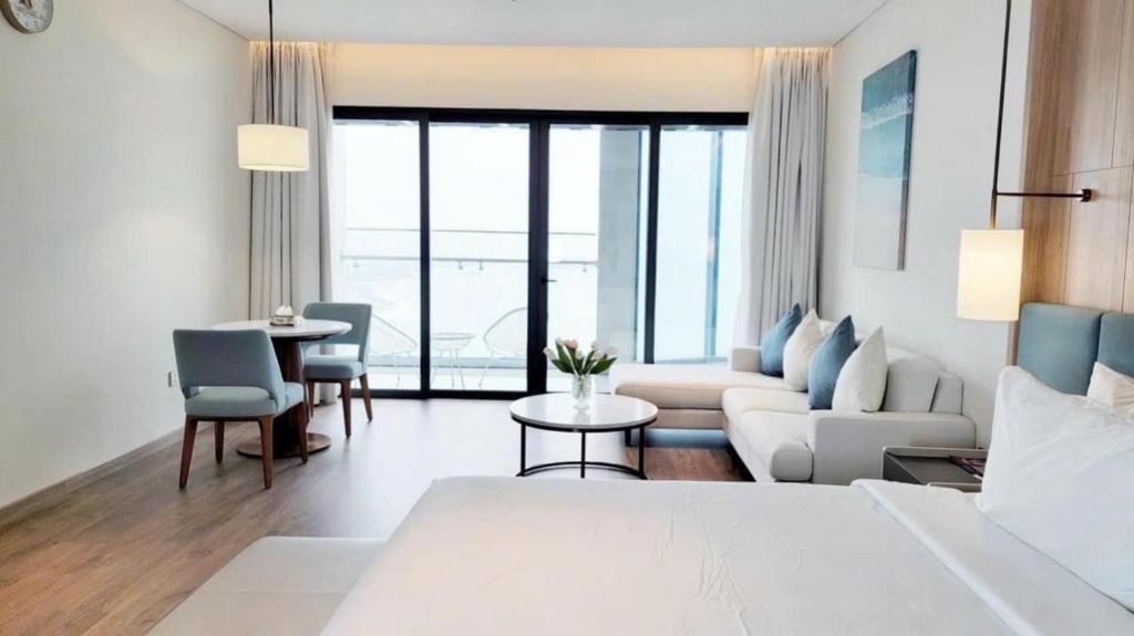 a hotel room with a bed and a living room at À La Carte Hạ Long in Ha Long