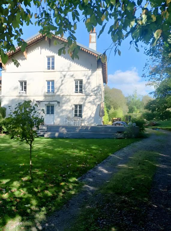 a large white house with a tree in the foreground at Chambre d'hôtes Le Colibri in Épinal