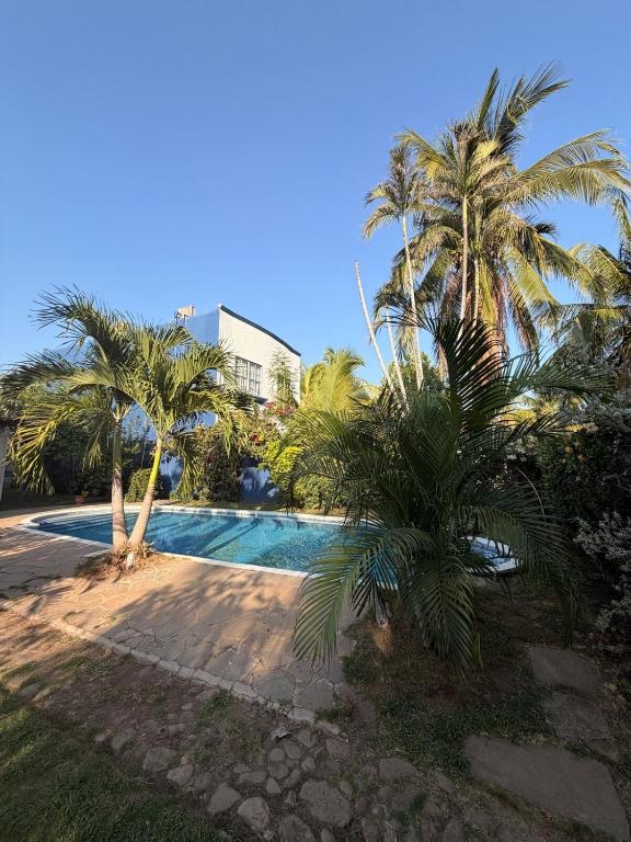 a swimming pool with palm trees next to a building at Cozy beach house getaway in La Libertad