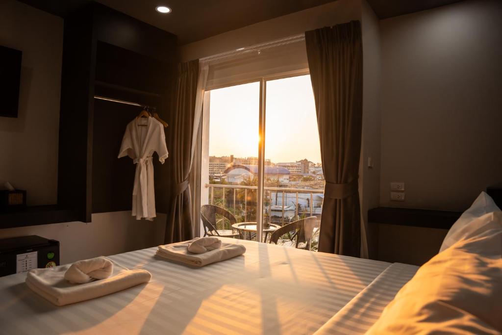 a bedroom with a bed with towels on it with a window at Aslan Boutique Apartments in Patong Beach