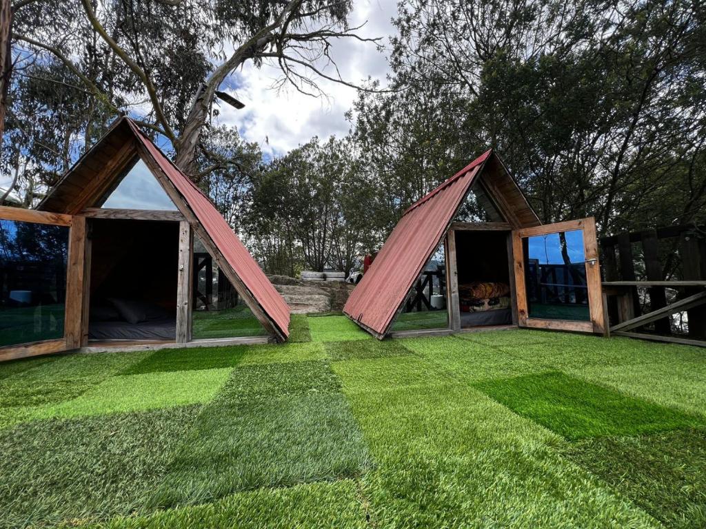 a house with a triangular roof on a lawn at Mini Cabaña Roca Glamping in Suesca