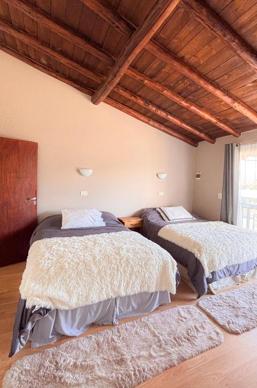 two beds in a room with wooden ceilings at Trono de Nubes in Trevelín