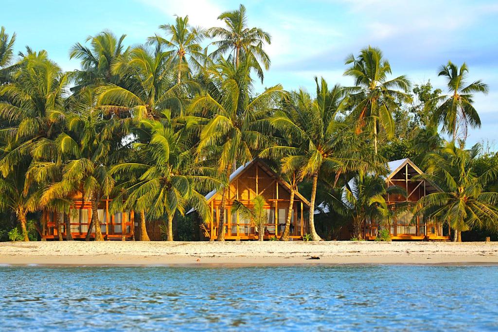 a resort on a beach with palm trees and the water at Ombak Biru Resort in Tua Pejat