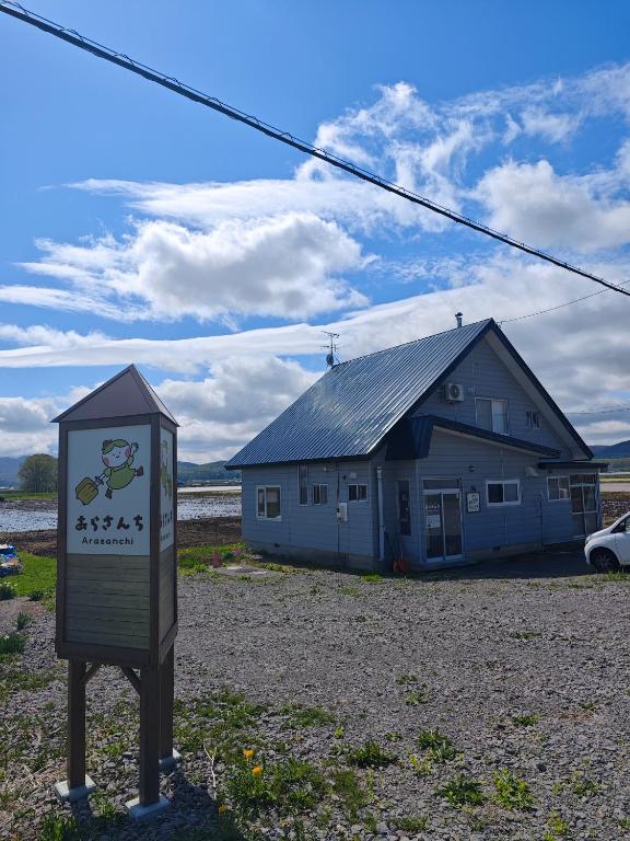 ein Schild vor einem Haus mit einem Gebäude in der Unterkunft あらさんち in Asahikawa