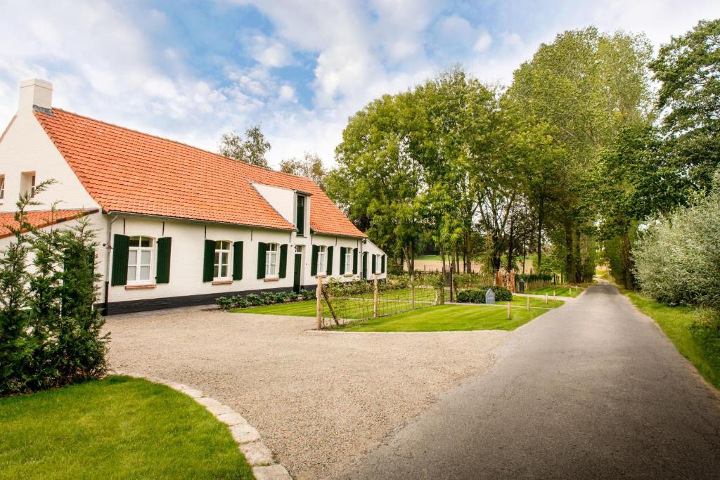 ein weißes Haus mit einem roten Dach und einer Auffahrt in der Unterkunft Cottage de Vinck in Ypern