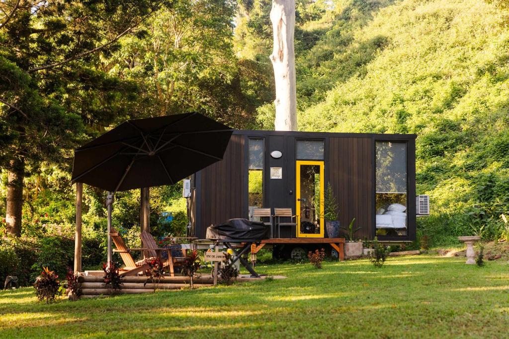 a black tiny house with an umbrella in the grass at Montville Retreat by Tiny Away in Montville