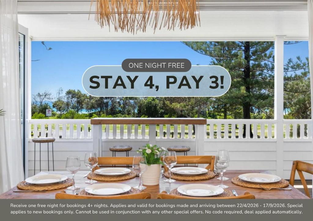 a table with chairs and a sign that reads stay pay three at Oceanfront Beach House On Marine Parade in Kingscliff
