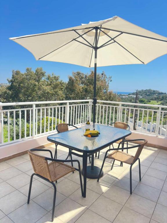 a blue table with chairs and an umbrella on a balcony at Bougainvillea Retreat above Faliraki in Kalithies
