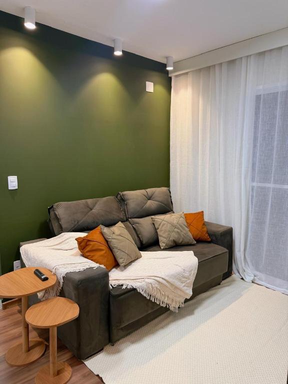a couch in a living room with a green wall at Apartamento com academia - Toledo in Toledo