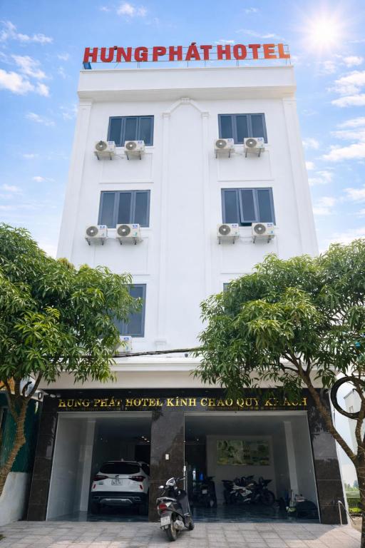 a white hotel with a car parked in front of it at Hưng Phát Hotel Nghệ An in Vinh
