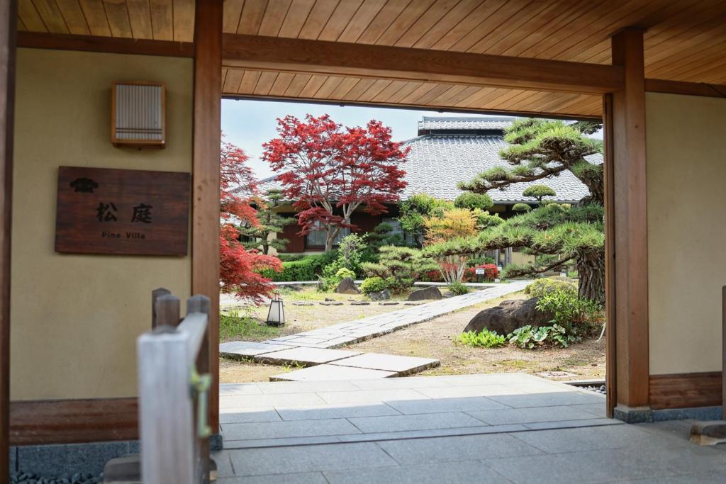 an open door to a garden with trees and bushes at Kansai Airport Hotel Pine Villa in Kansai International Airport