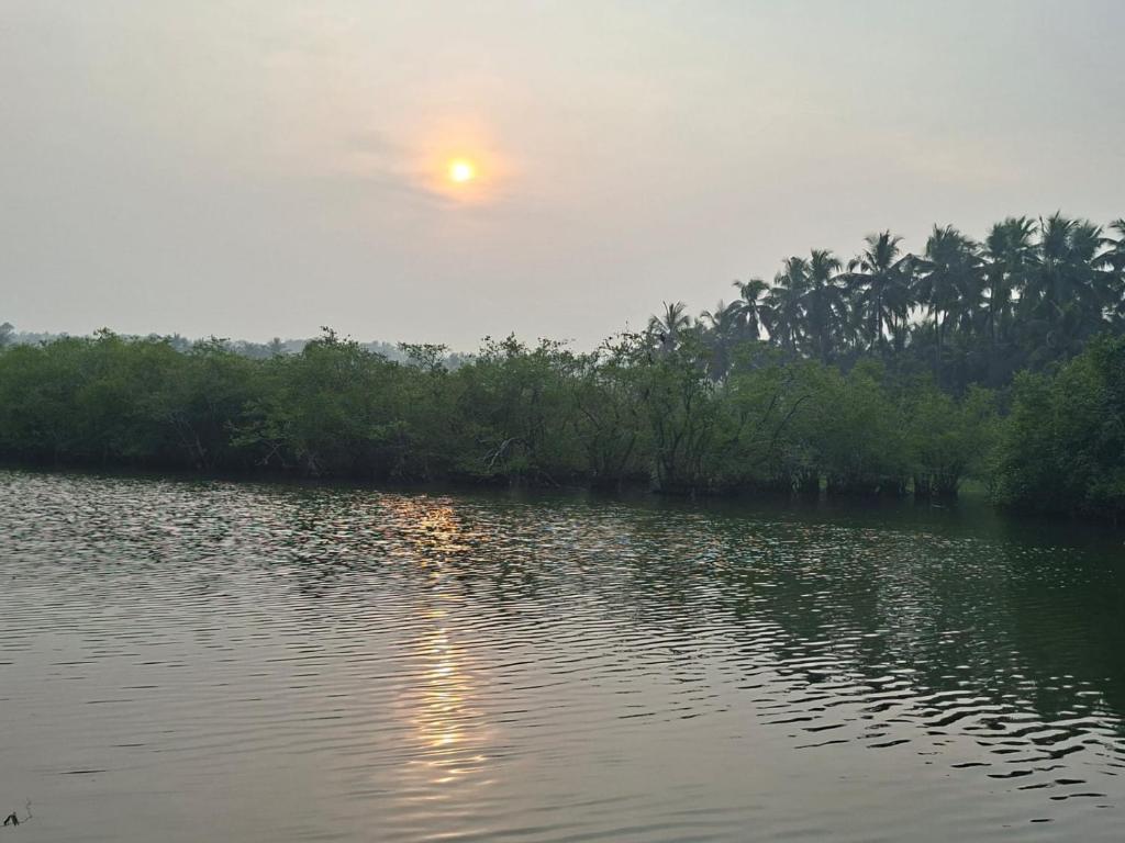 a sunset over a body of water with trees at Kkheritage Homestay in Thottada