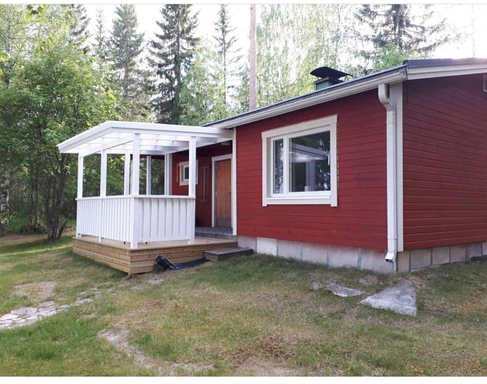 a red house with a porch and a window at Pääsky Schwalbe-cabin by crater lake in Varpaisjärvi