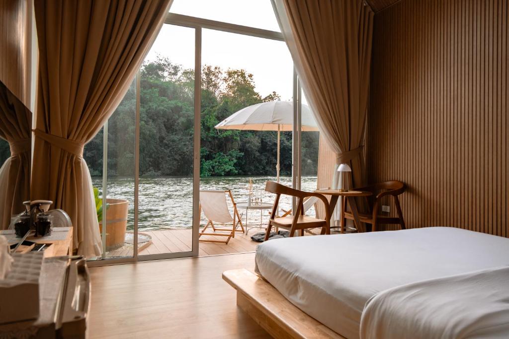 a bedroom with a bed and a view of the water at Baanpufa Resort in Sai Yok