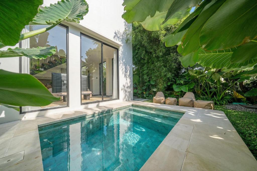 a swimming pool in a garden with a house at Lily Villas - Rice Field Views Escape with Private Pool in Canggu
