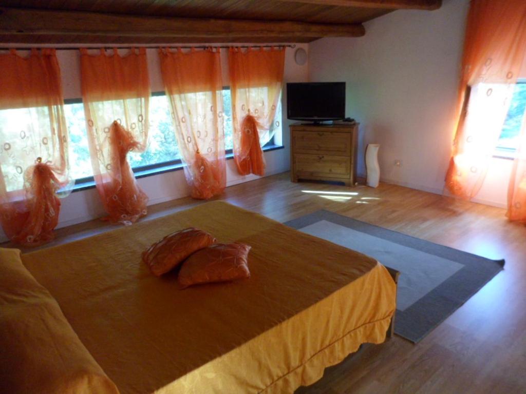 a bedroom with a bed with orange curtains and a television at Casa Vacanze Villa Paradiso in Maratea