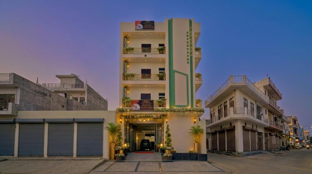 a tall white building with a doorway and two buildings at Hotel Sangree in Jewar