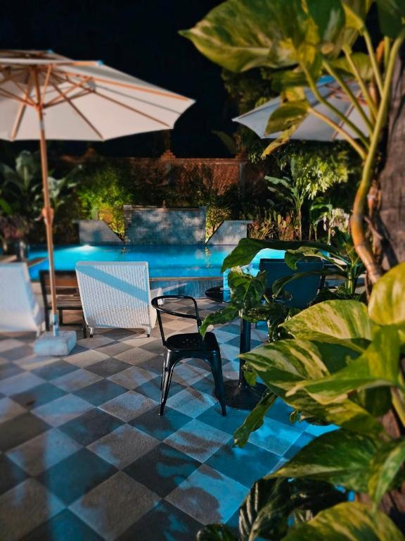 a patio with chairs and an umbrella and a pool at Angkor Rise Residence in Siem Reap